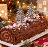 Bûche de Noël au chocolat décorée de deux sapins argentés sur pique, avec décorations festives et ambiance de Noël chaleureuse.